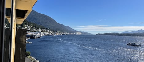 A coastal town with a pier extending into the water, surrounded by mountains.