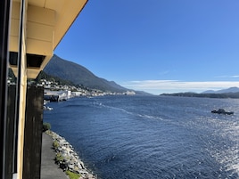 A coastal town with a pier extending into the water, surrounded by mountains.