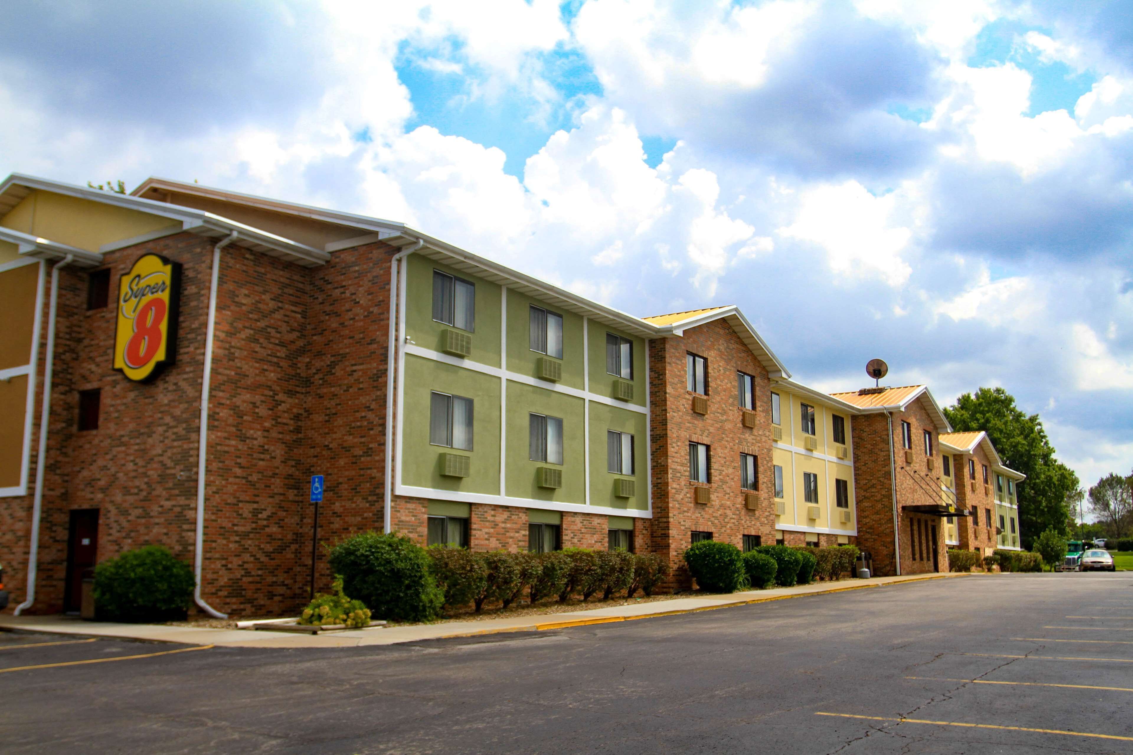 A hotel with a brick facade, multiple windows, and a parking lot.