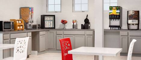 A modern kitchen with a white countertop, a red chair, and a coffee machine.