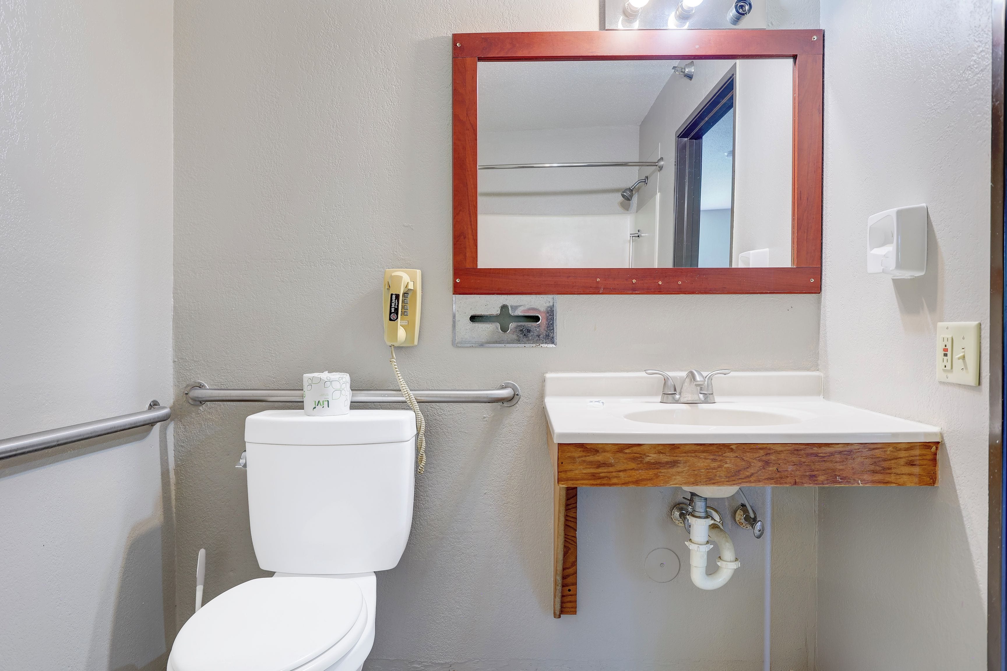 Un baño con inodoro, lavamanos, espejo y secamanos.