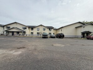 A multi-story motel with a parking lot, several vehicles, and a bicycle. - Coldwater Inn & Suites near I 69 (Coldwater)