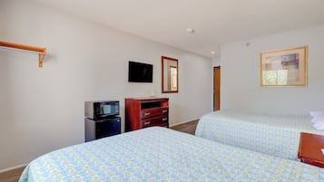 A hotel room with two beds, a dresser, a television, and a mirror.