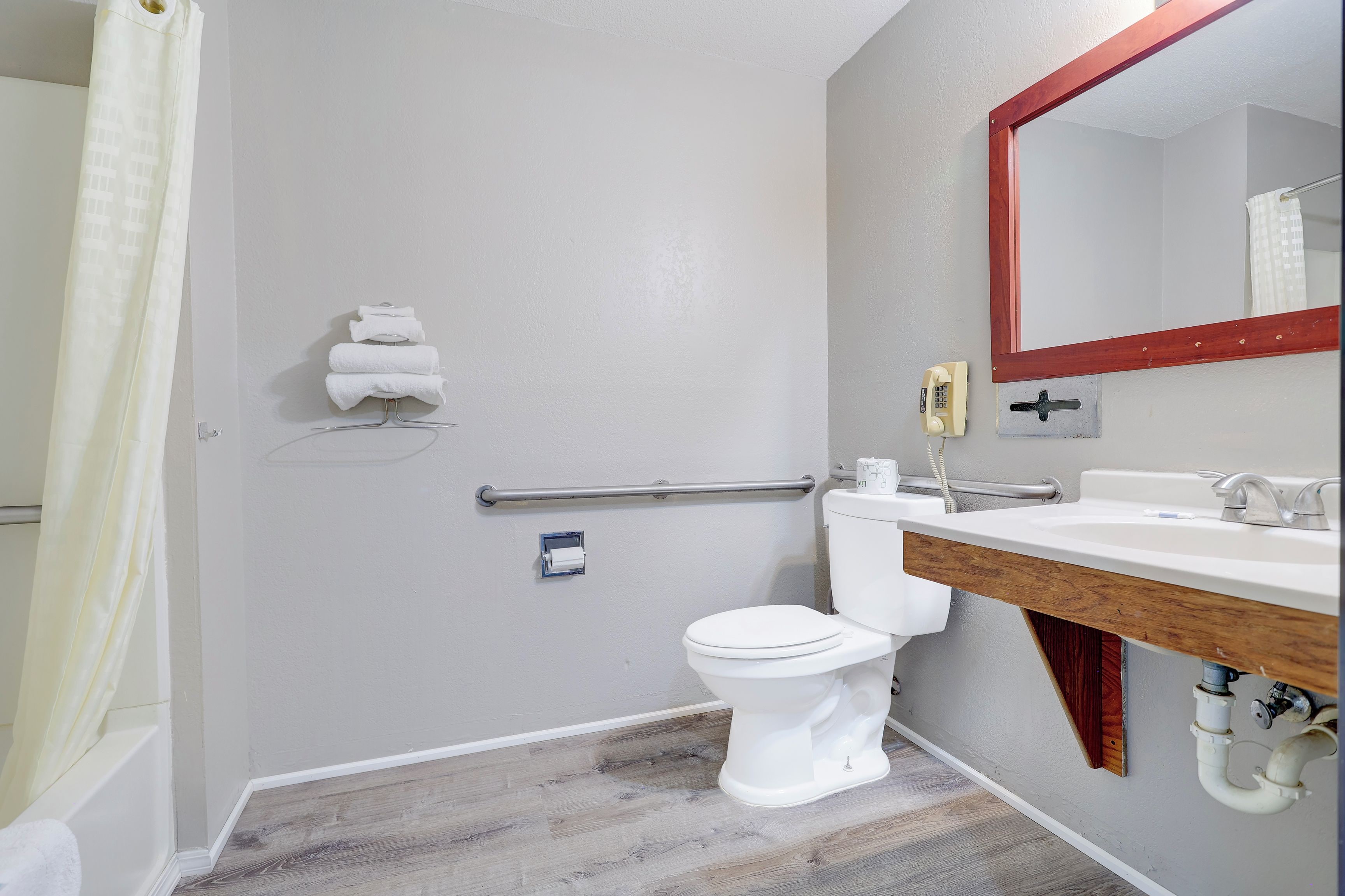 A bathroom with a toilet, sink, mirror, towel rack, and a shower curtain.