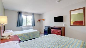 Une chambre d’hôtel avec deux lits, une télévision, une commode et une fenêtre avec des rideaux.