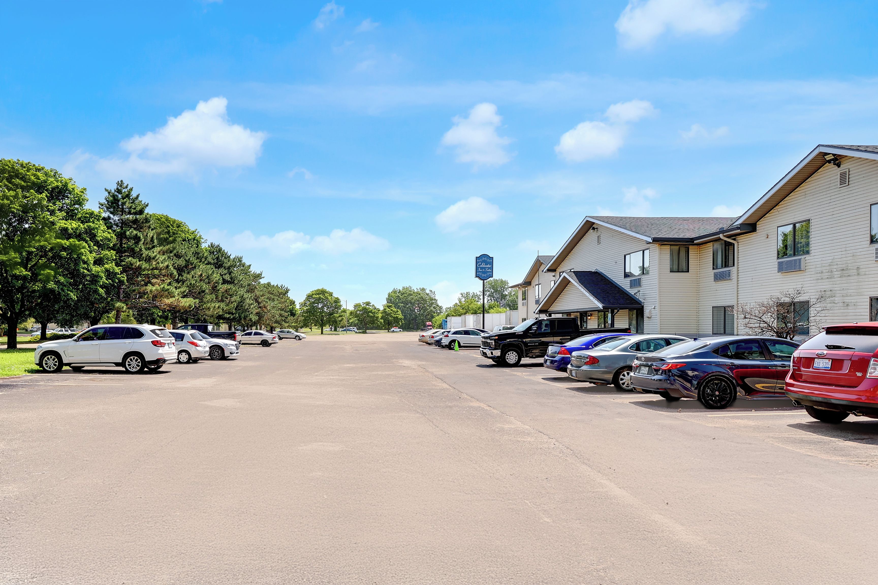 A parking lot with multiple cars parked in front of a building with a blue sign.