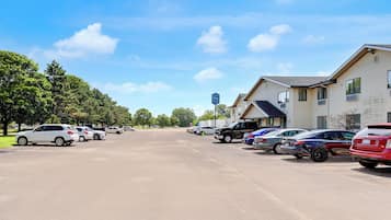A parking lot with multiple cars parked in front of a building with a blue sign.