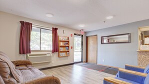 A room with a sofa, a chair, a bookshelf, and a door. - Coldwater Inn & Suites near I 69 (Coldwater)