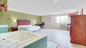 A hotel room with a large bathtub, two beds, a desk, and a window. - Coldwater Inn & Suites near I 69 (Coldwater)