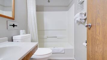 A bathroom with a toilet, a shower, and a sink.