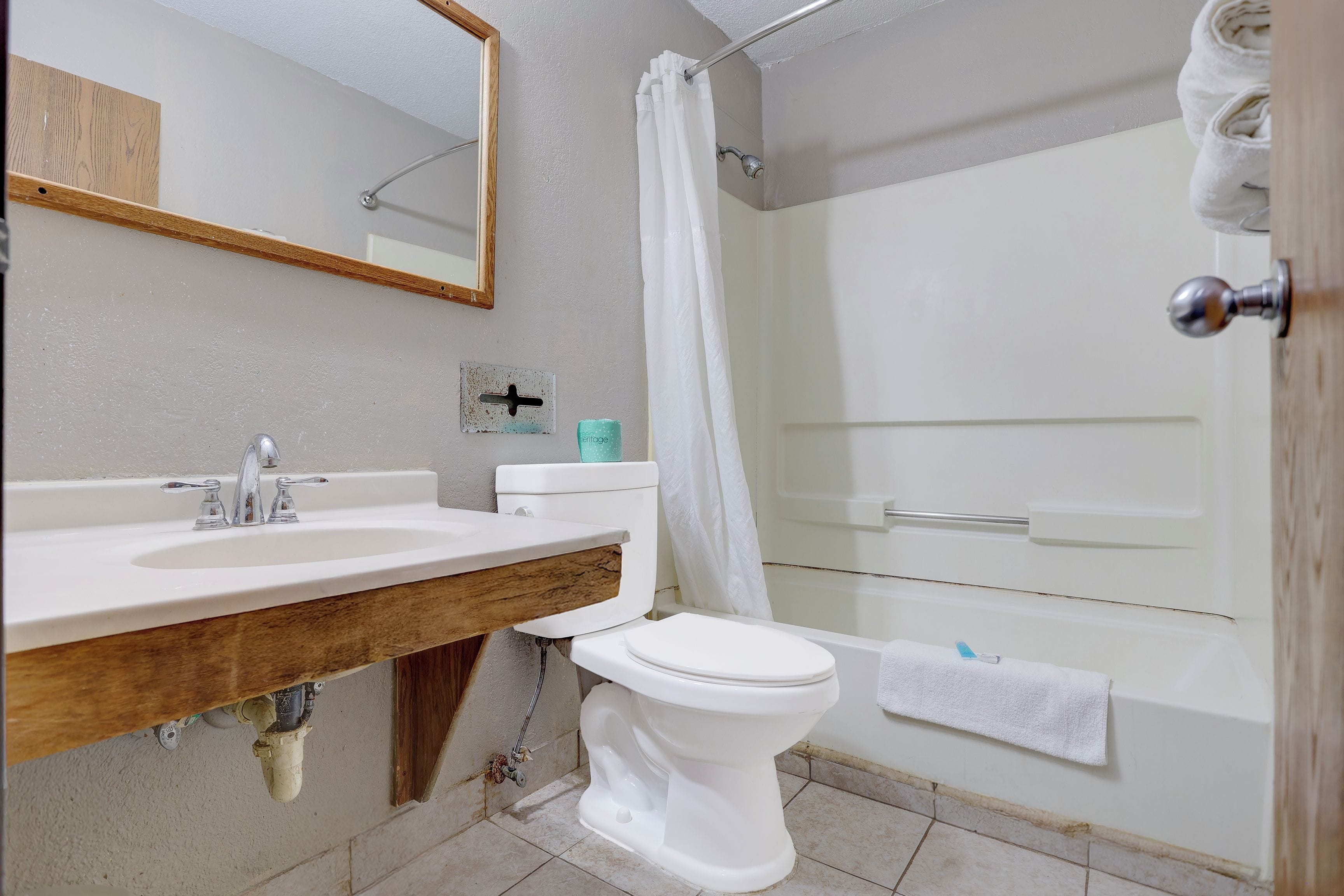 Un baño con tocador de madera, inodoro blanco, ducha con puerta de vidrio y bañera.