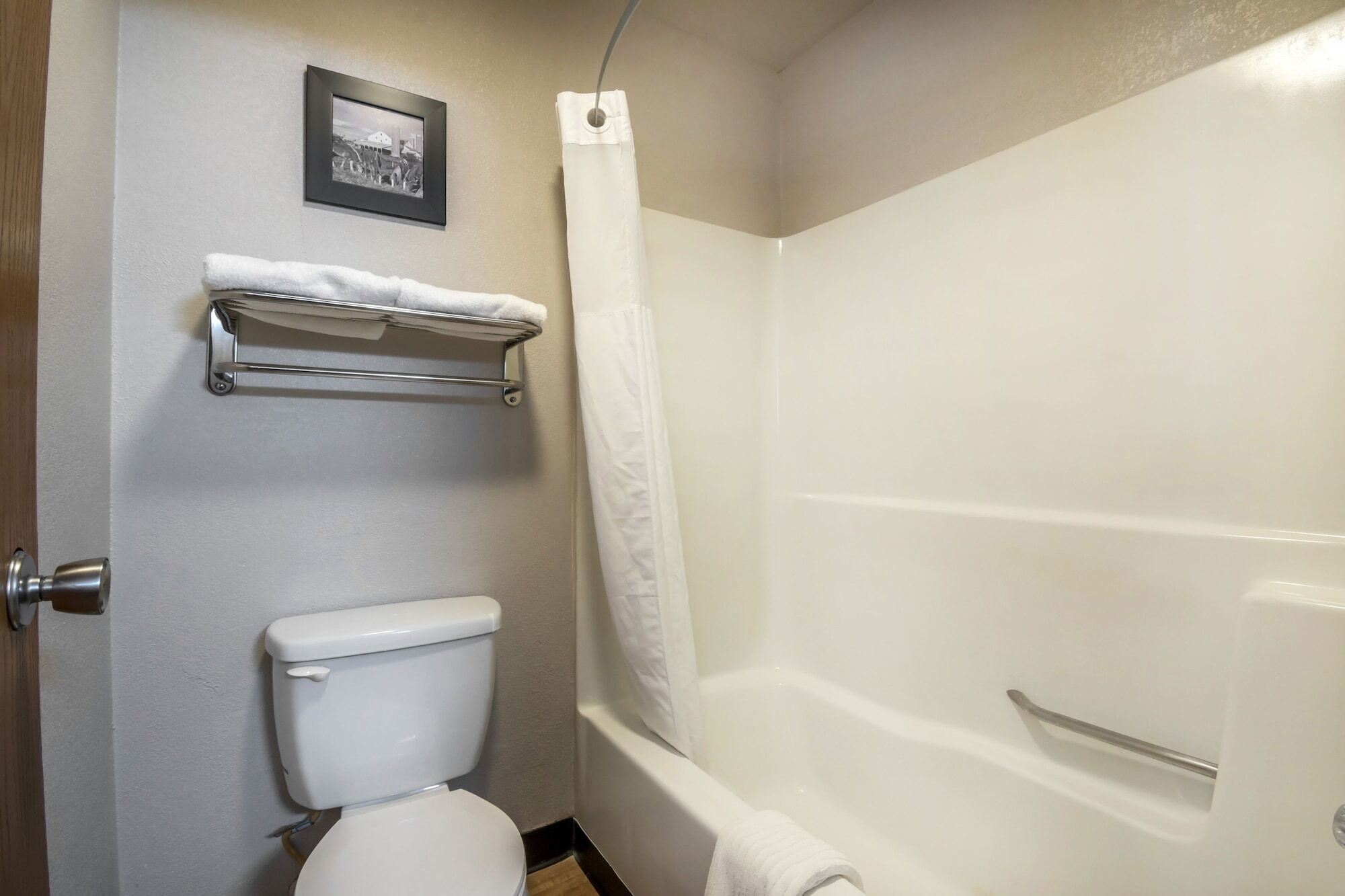 A bathroom with a toilet, a shower with a curtain, and a towel rack.
