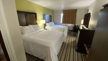 A hotel room with two beds, a desk, a chair, a TV, and a window with curtains.