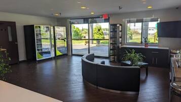 A reception area with a curved black seating area, a glass door entrance, and a view of the outdoors.