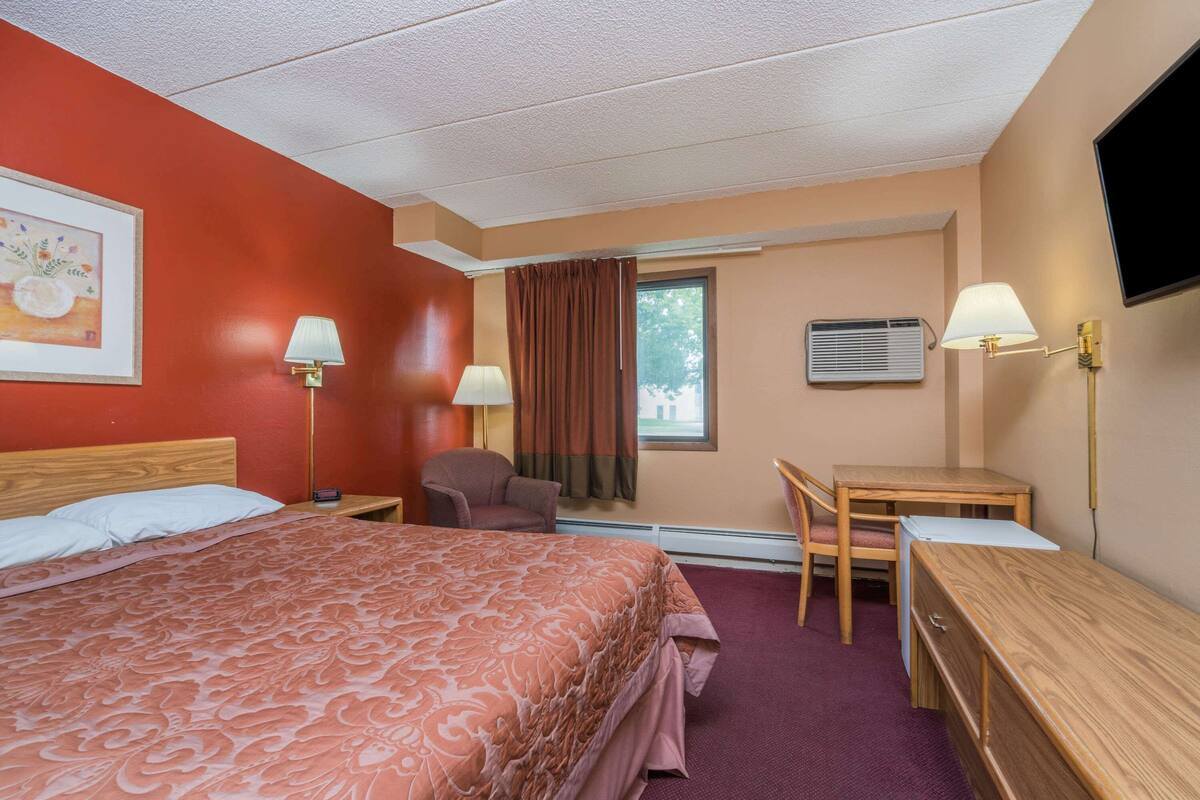 Une chambre d’hôtel équipée d’un lit, d’un bureau, d’une chaise, d’une télévision et d’un appareil de climatisation.