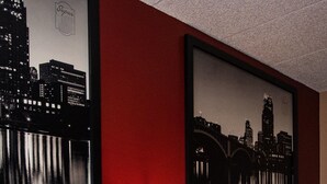 Une chambre d’hôtel avec deux lits, une table de chevet avec une lampe et un tableau représentant un paysage urbain accroché au mur.