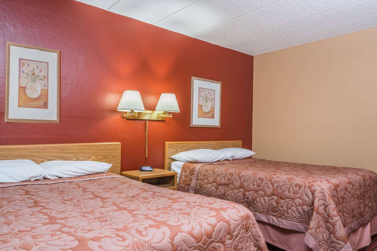 Une chambre d’hôtel avec deux lits, une table de chevet et des lampes fixées au mur.