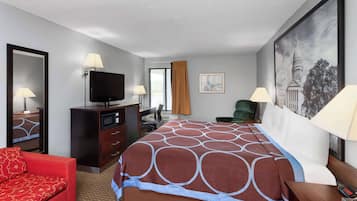 Una habitación de hotel con una cama grande, un sofá rojo, un escritorio con televisor y un cuadro en la pared.