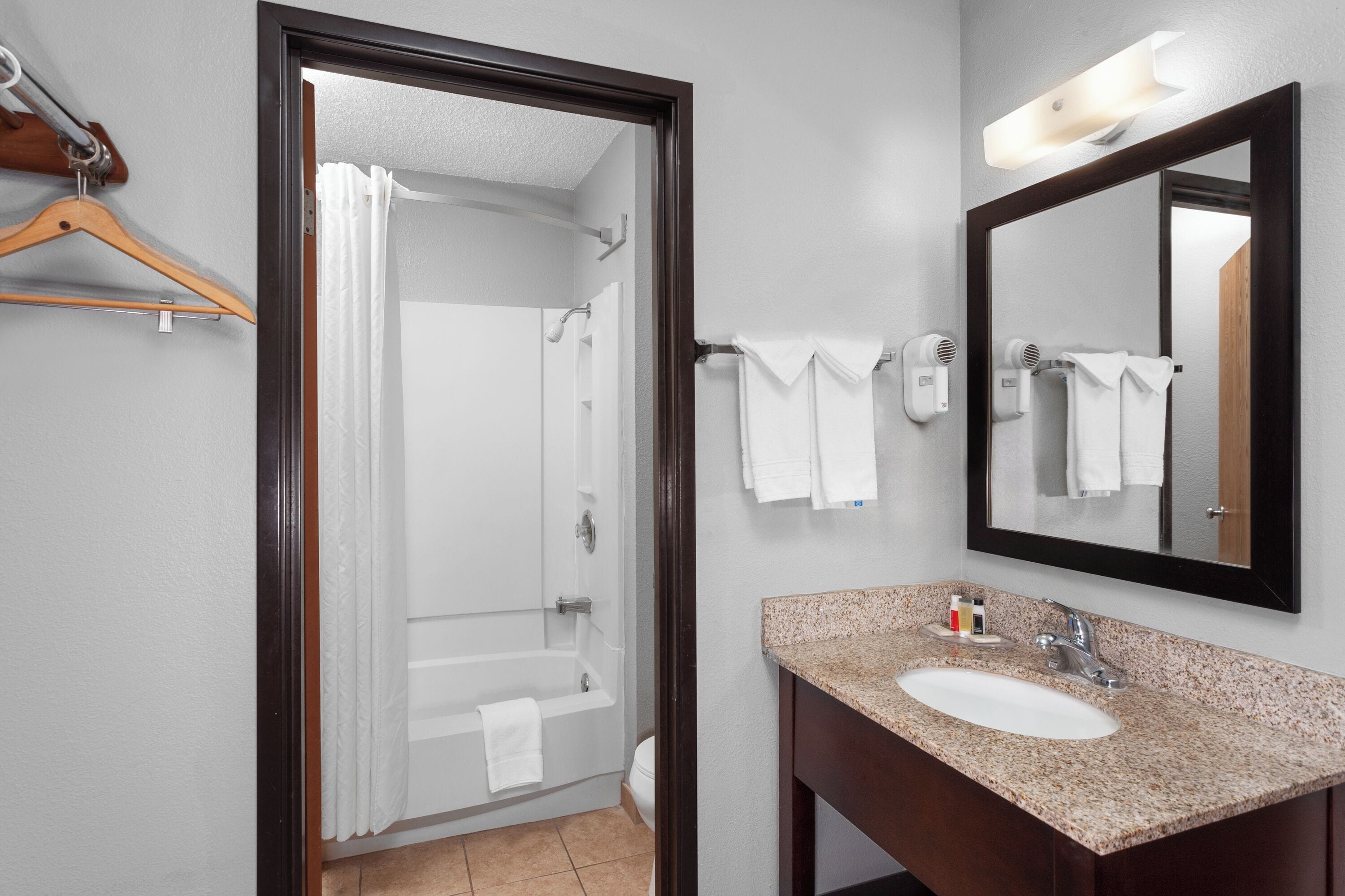 Baño con lavamanos, espejo, toallero y ducha.