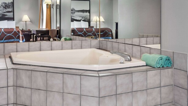 A modern bathroom with a large freestanding bathtub, a mirror, and a towel rack. - Super 8 by Wyndham Sun Prairie/Madison E (Sun Prairie)