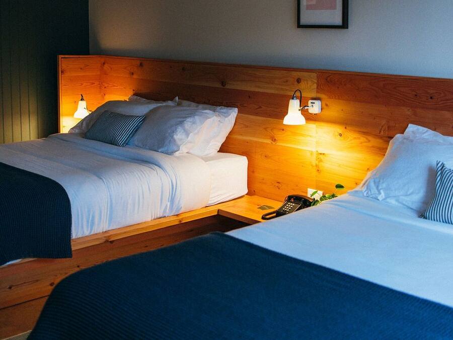 Una habitación de hotel con dos camas, cabeceros de madera y lámparas de noche.
