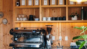 A coffee shop interior with wooden shelves, a coffee machine, and a checkered table.