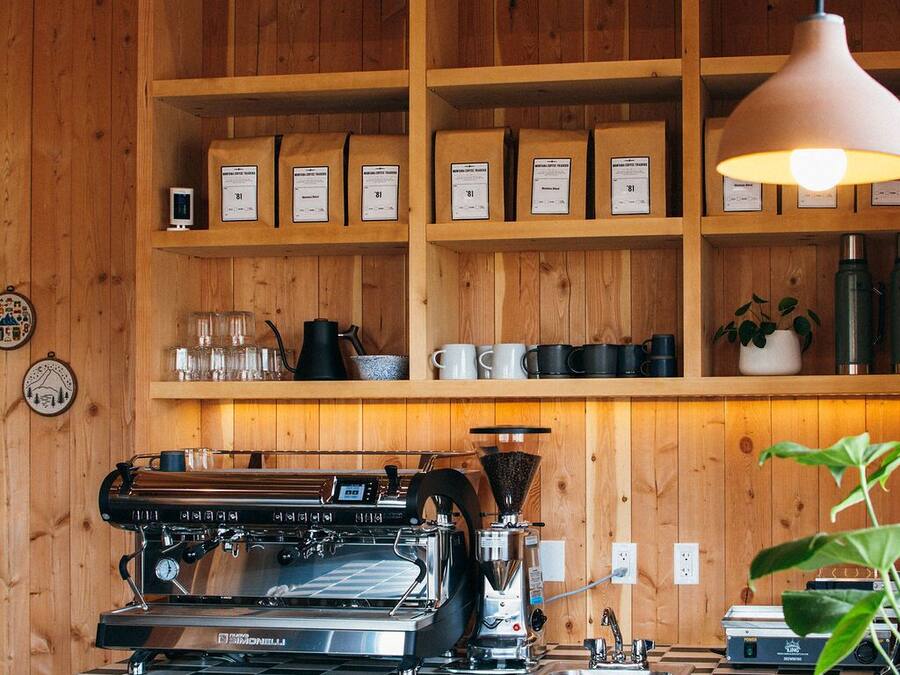 A coffee shop interior with wooden shelves, a coffee machine, and a checkered table.