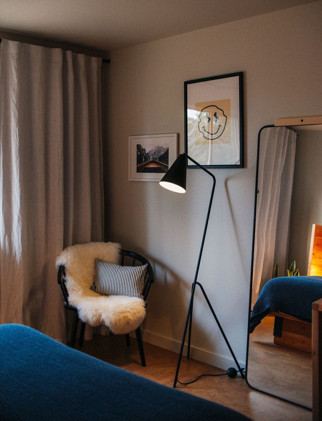 Una habitación con un sillón de piel, una lámpara de pie, una cama y un cuadro en la pared.
