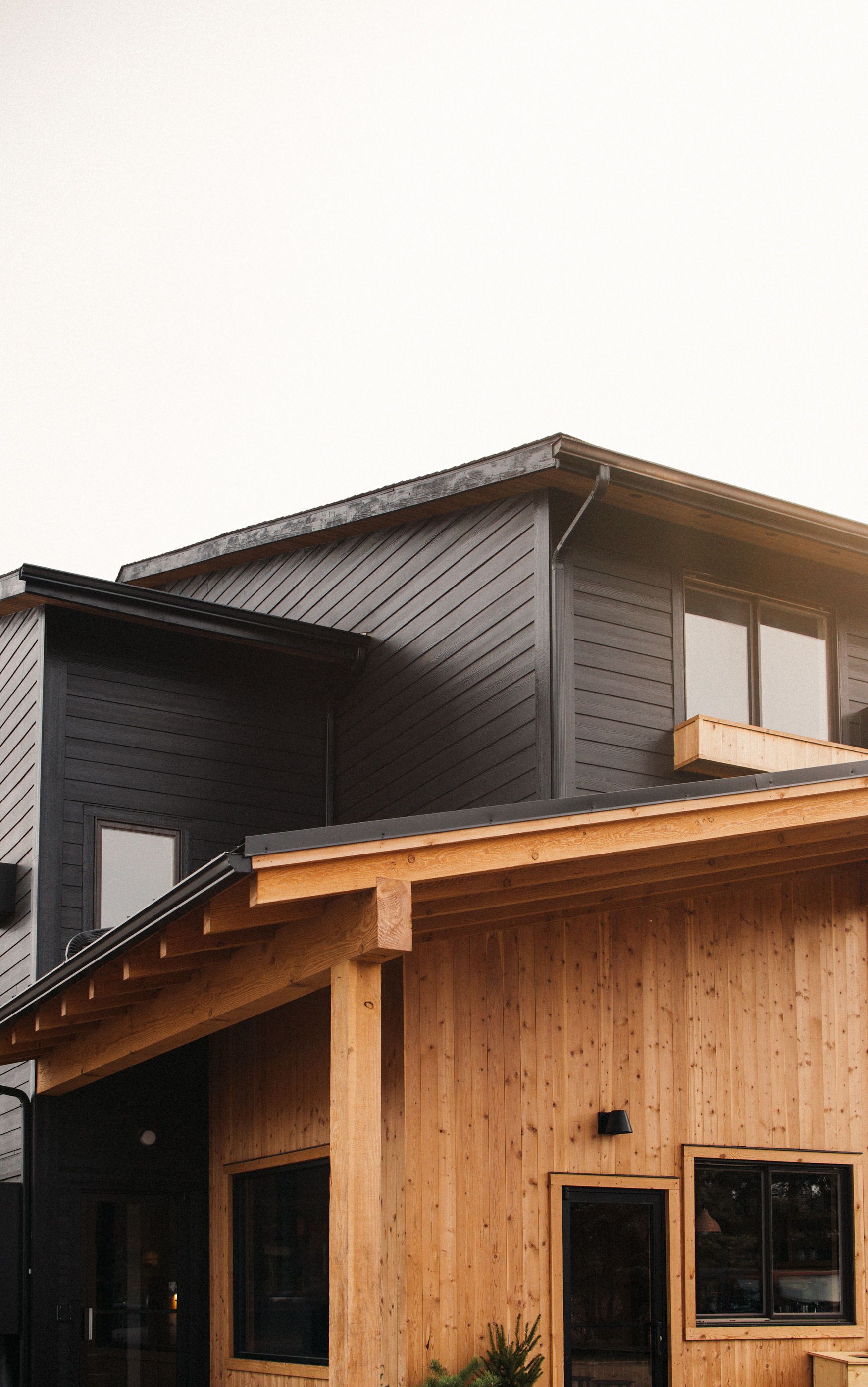 A modern two-story house with a dark exterior and wooden accents.