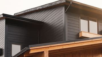A modern two-story house with a dark exterior and wooden accents.