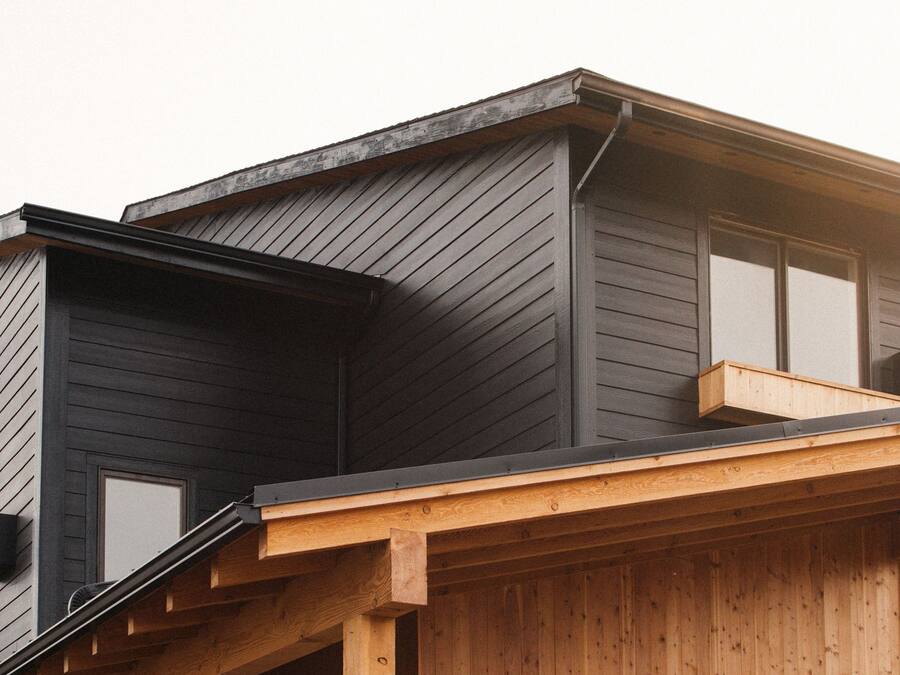 A modern two-story house with a dark exterior and wooden accents.