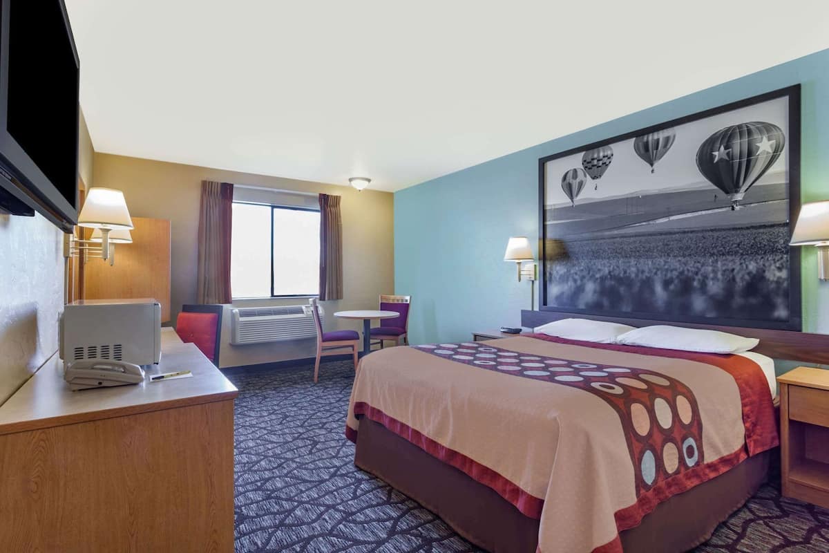 Una habitación de hotel con cama, escritorio, silla y un ventanal grande.