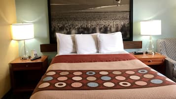 Una habitación de hotel con una cama, dos lámparas de noche, un cuadro enmarco con globos aerostáticos y una colcha estampada.