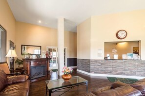 A hotel lobby with a reception desk, a fireplace, leather sofas, and a coffee table.