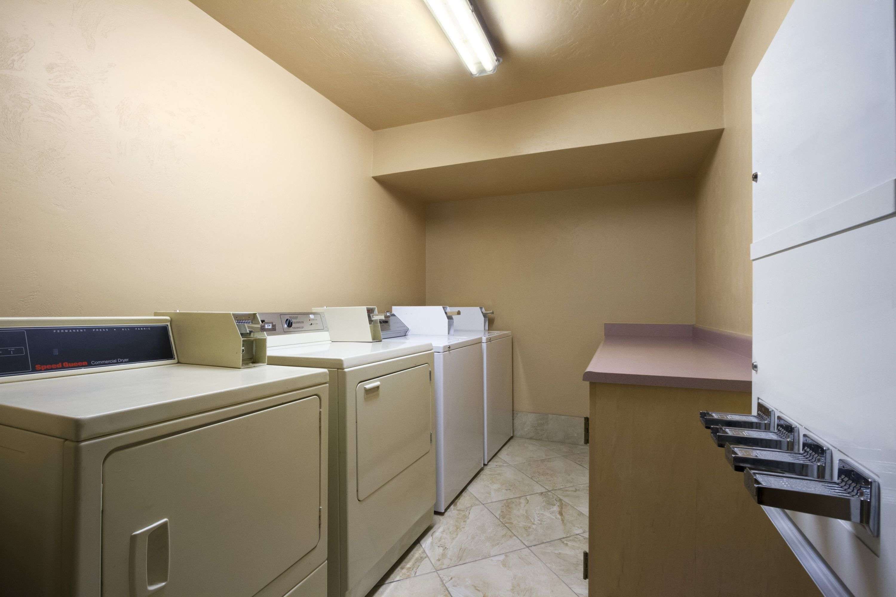 A laundry room with a commercial dryer, washing machine, and a sink.