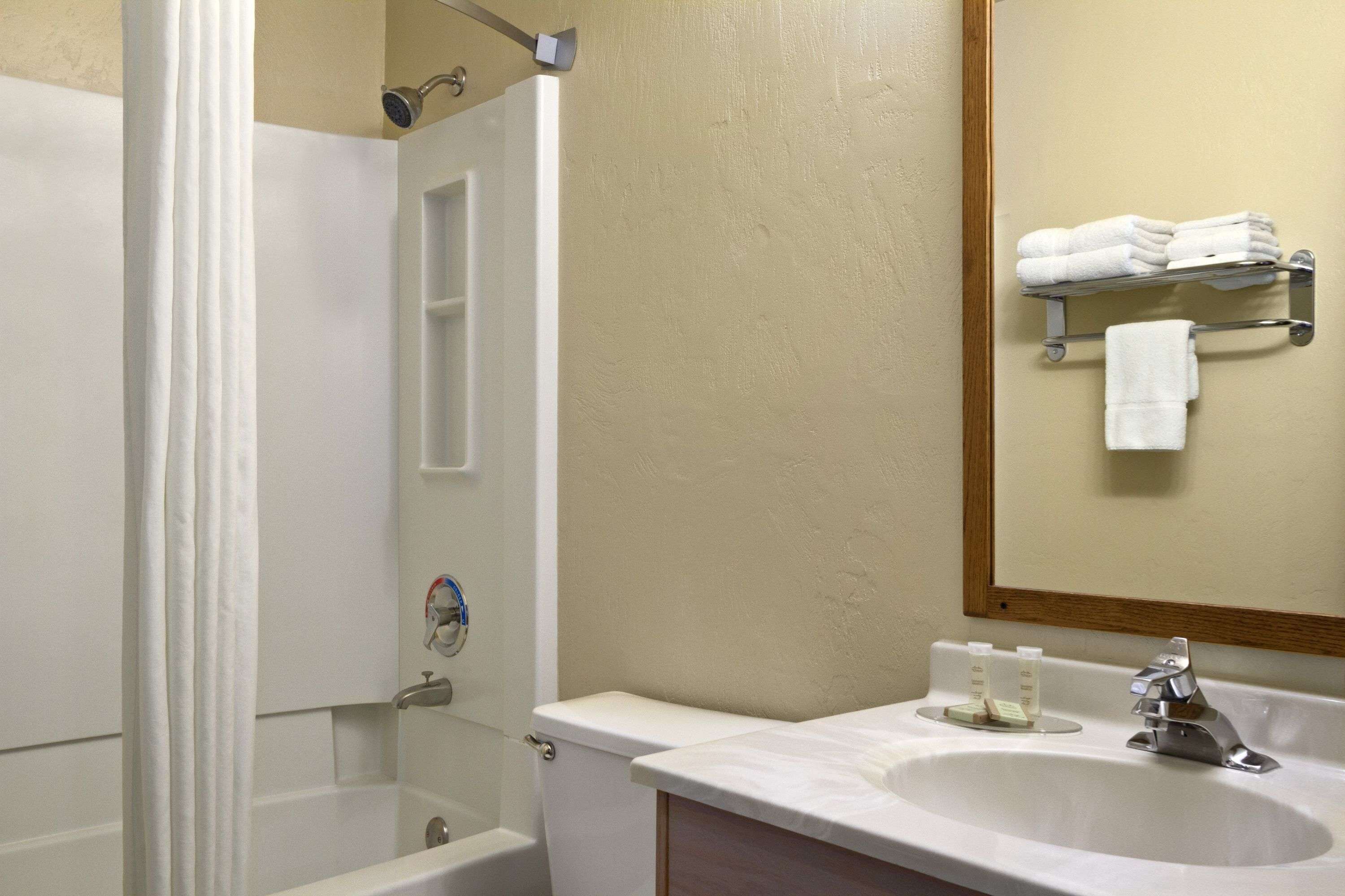 A bathroom with a bathtub, a sink, a mirror, and a towel rack.