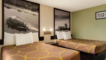 Habitación de hotel con dos camas, cada una con colcha estampada, vista a la ciudad y un cuadro en la pared.