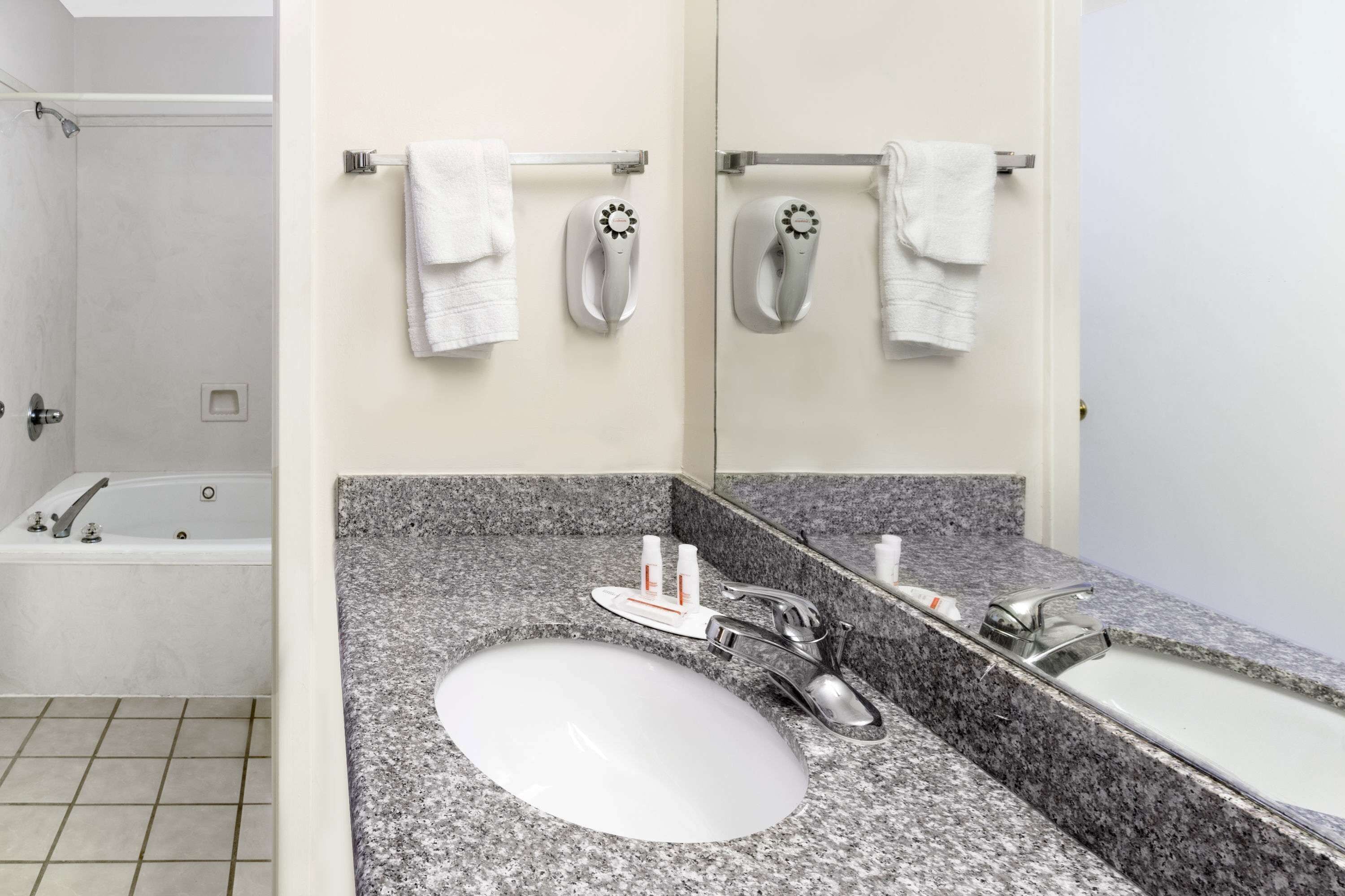 Ein Badezimmer mit Granitplatte, Waschbecken, Badewanne und Spiegel.