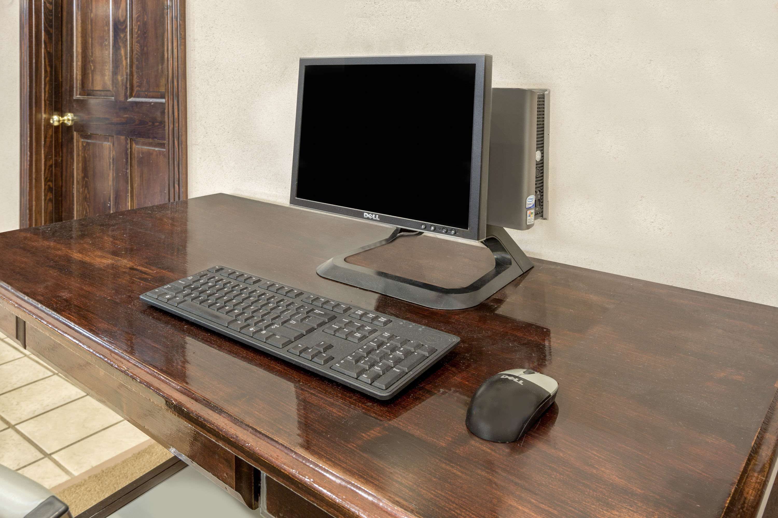 Un bureau en bois avec un écran, un clavier et une souris de la marque Dell.