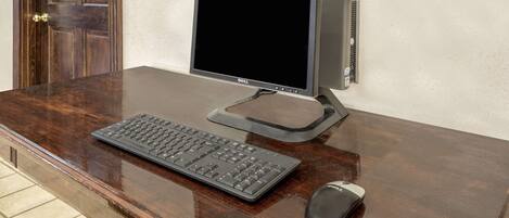 A wooden desk with a Dell monitor, keyboard, and mouse.