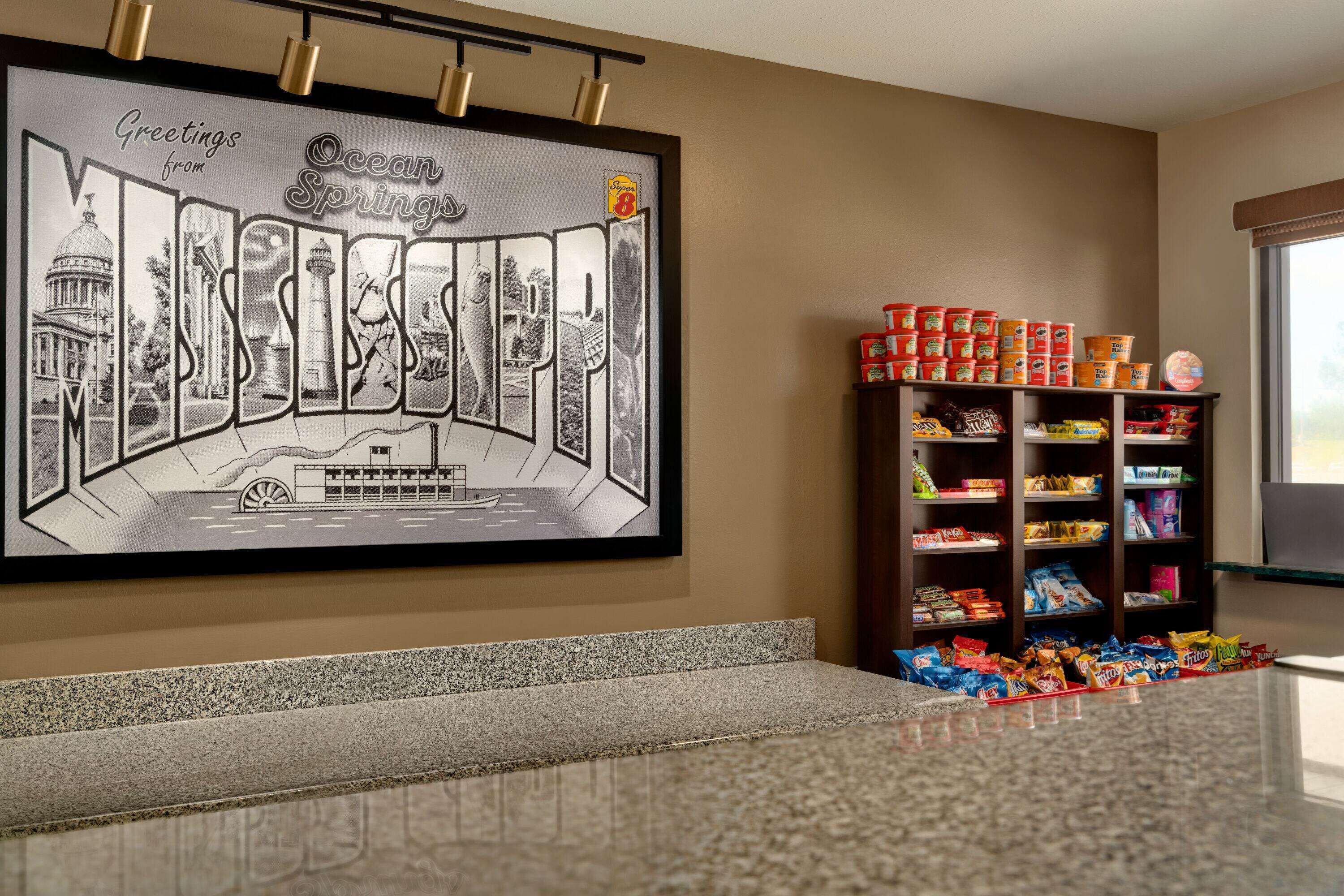 A framed welcome sign with city landmarks, a snack shelf, and a granite countertop.