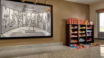 A framed welcome sign with city landmarks, a snack shelf, and a granite countertop.