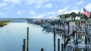 A marina with boats docked, a flagpole with an American flag, and a distant shoreline. - Super 8 by Wyndham Ocean Springs Biloxi (Ocean Springs)