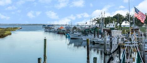 A marina with boats docked, a flagpole with an American flag, and a distant shoreline.