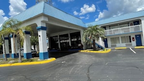 Un motel con techo azul, cielo despejado y aparcamiento.