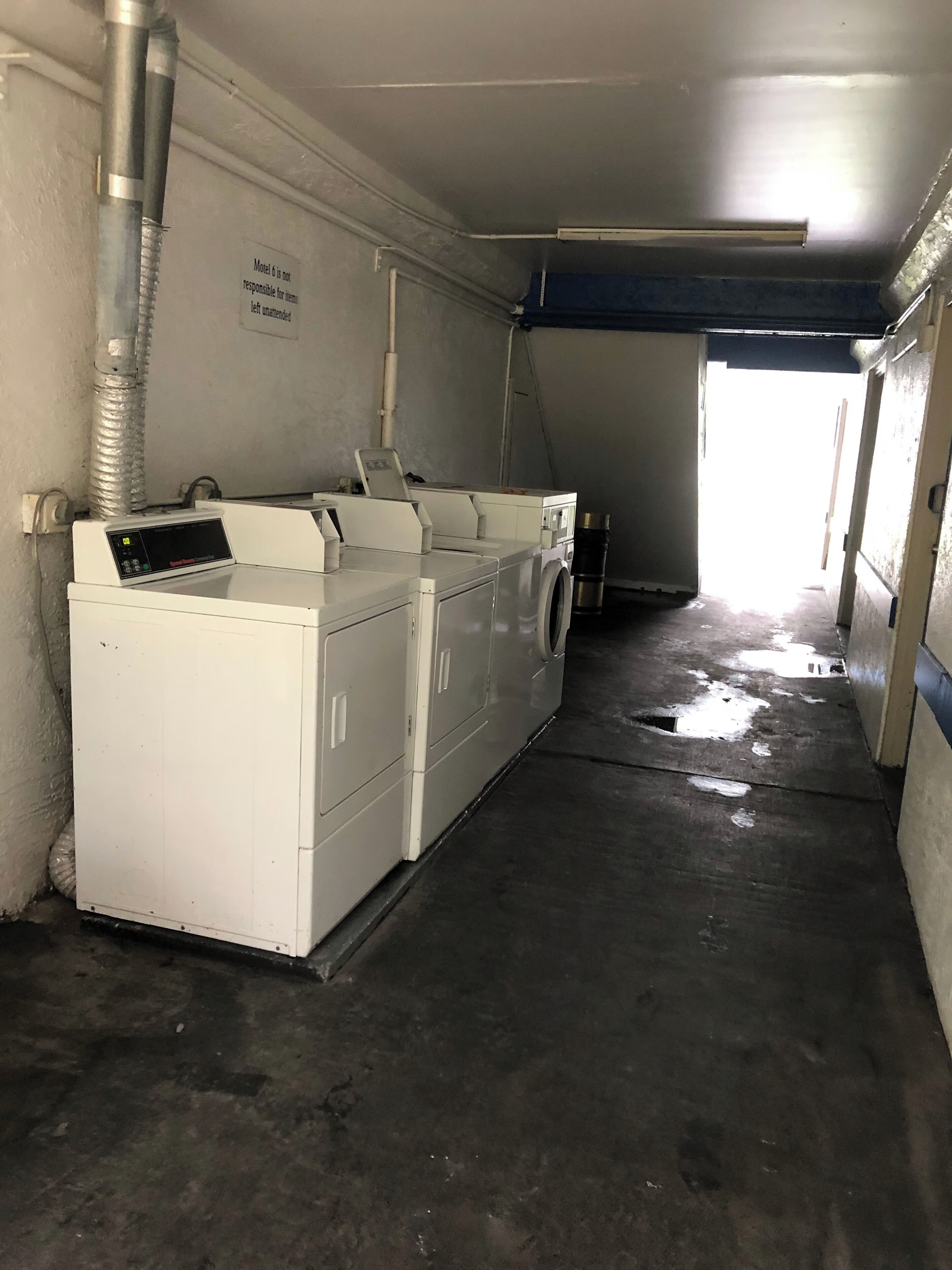 Une buanderie équipée d’un lave-linge, d’un sèche-linge et d’un panneau indiquant que cet espace est réservé au personnel et non accessible aux clients.