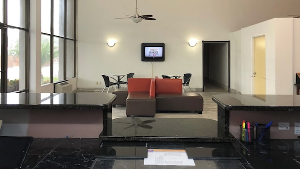 Un vestíbulo moderno con una zona de estar, una televisión y un mostrador de recepción.