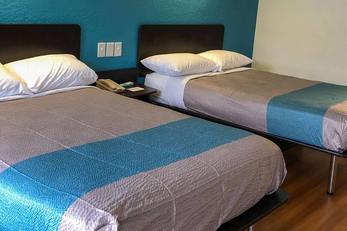 Two single beds with headboards, a bedside table with a phone, and a wall socket.