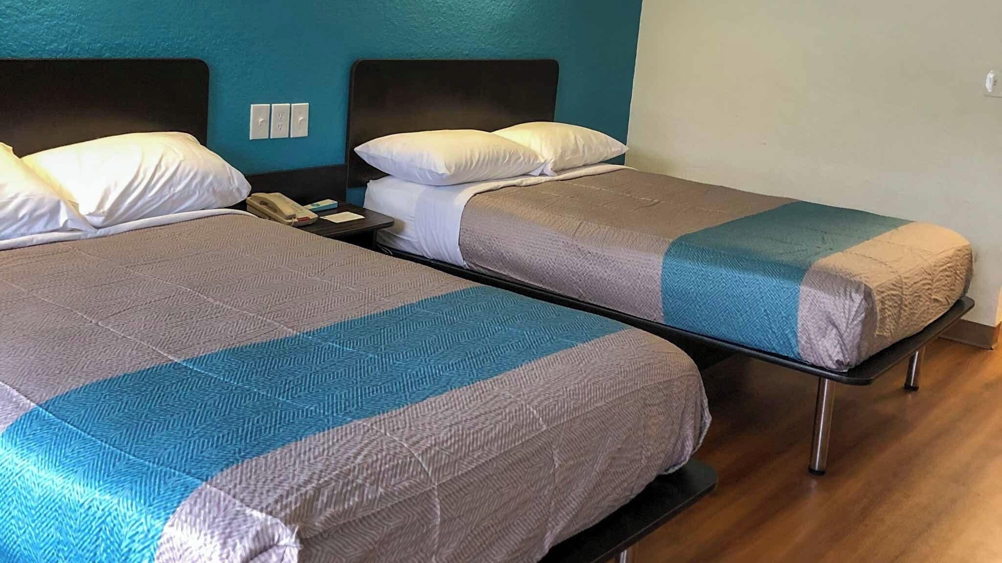 Two twin beds with headboards, a bedside table with a telephone, and a wall switch.
