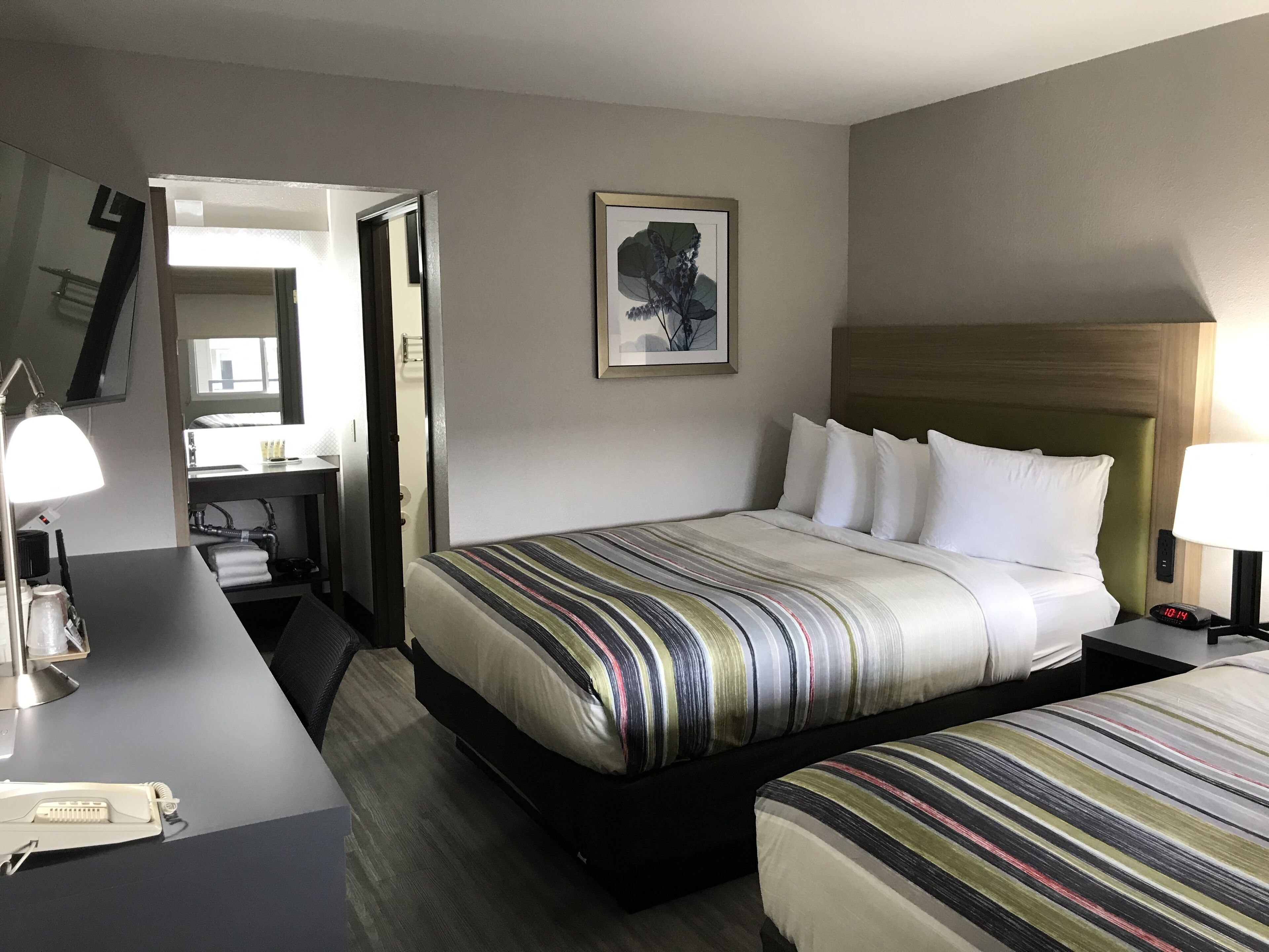 A hotel room with a bed, bedside table, lamp, and a mirror.
